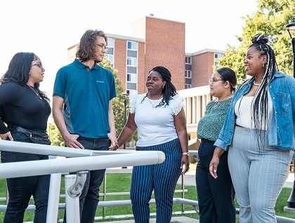 Students standing on campus with their staff mentor
