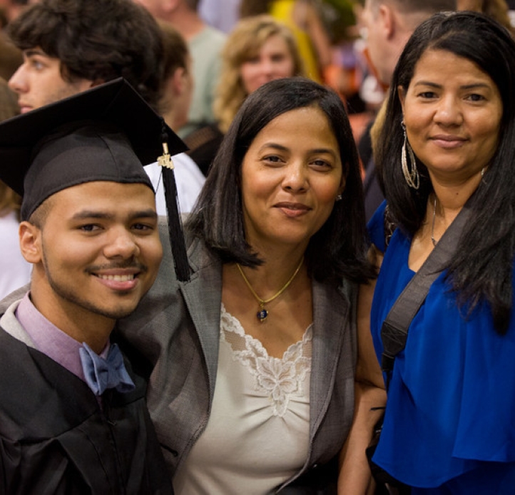 Graduate in cap and gown with family members