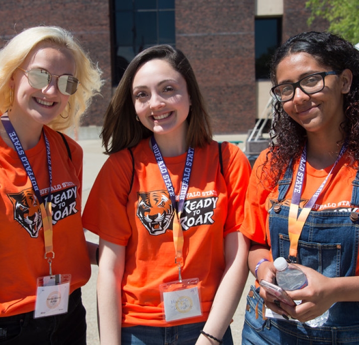 Three smiling students in Buffalo State T-shirts