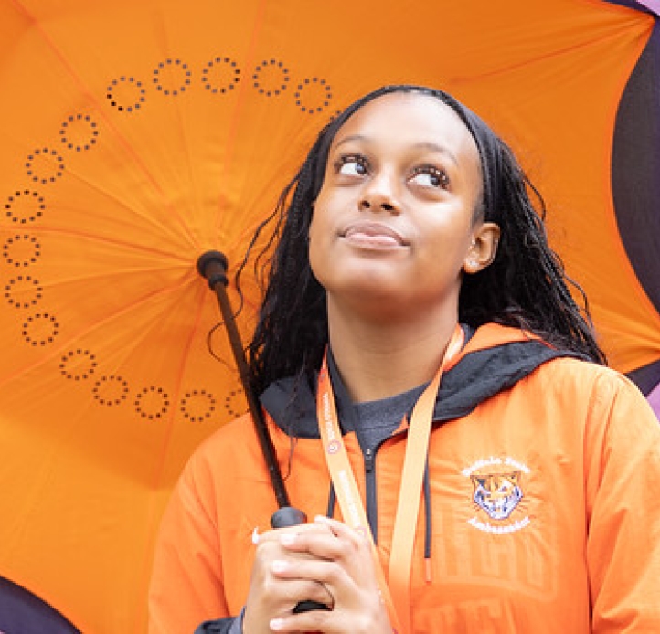 Buffalo State student under an orange umbrella