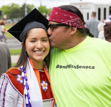 Father kissing daughter's cheek at commencement