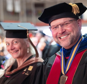 Two faculty members in academic regalia